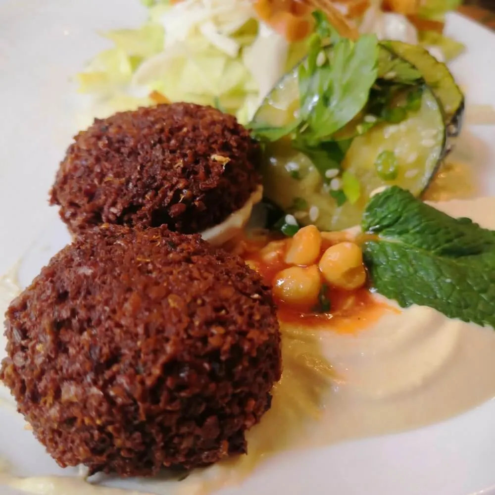 Zwei Falafelbällchen mit Hummus und Salat