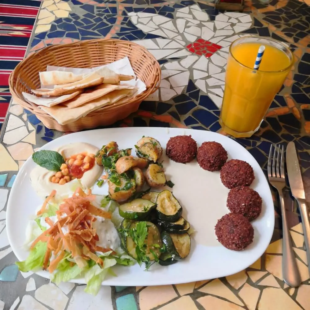 Falafelteller mit Antipasti, Hummus, Salat und einer Mangoschorle